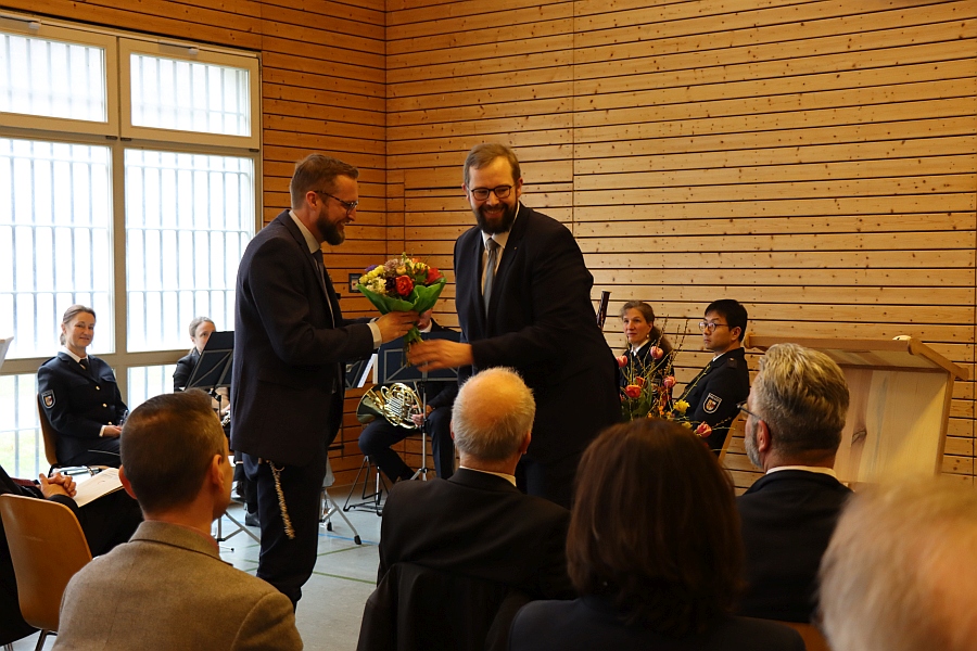 Das Bild zeigt die Übergabe eines Blumenstraußes nach dem Grußwort des 1. Stellvertreter des OB der Hansestadt Stralsund an den Anstaltsleiter.