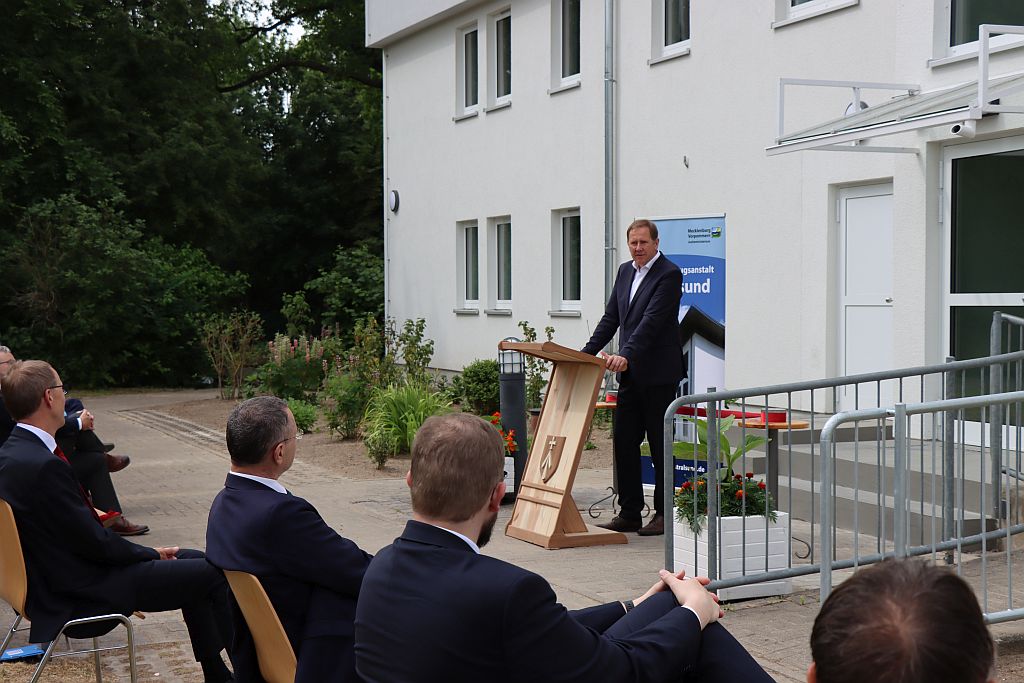 Staatssekretär Heiko Miraß steht am Rednerpult vor dem Hafthaus und spricht zu den Gästen