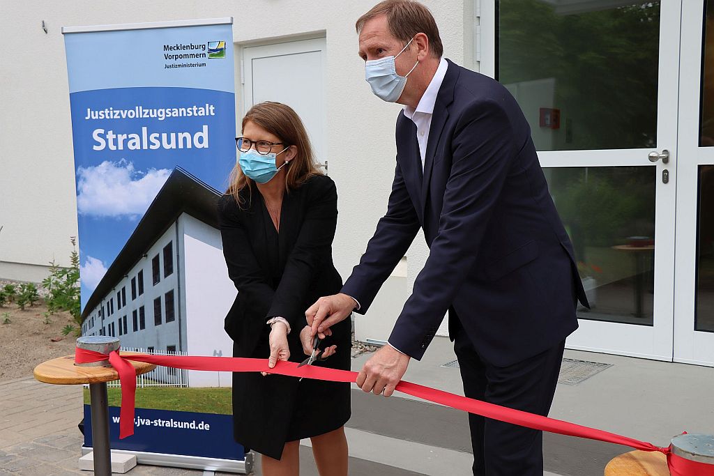 Justizministerin Katy Hoffmeister und Staatssekretär Heiko Miraß schneiden mit einer Schere ein rotes Band durch.