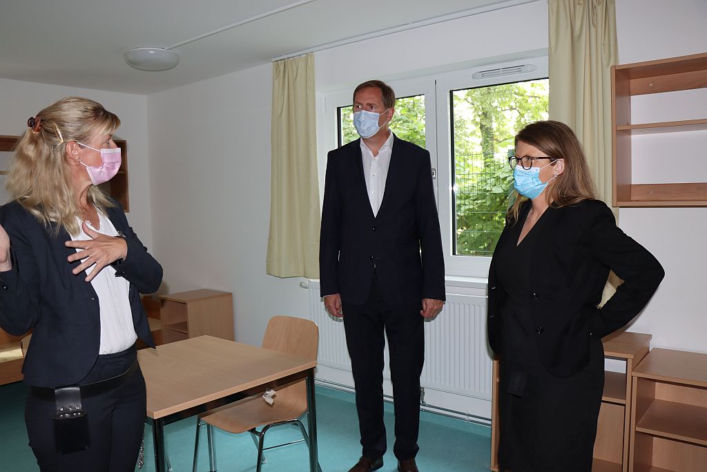 Drei Personen stehen in einem Raum. Sie unterhalten sich.